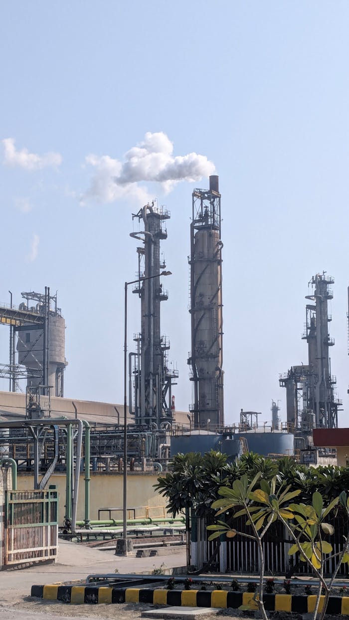 A detailed view of a chemical plant's tall chimneys and industrial structures against a clear sky.